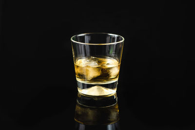 Scotch whiskey in a glass, with ice cubes, black background