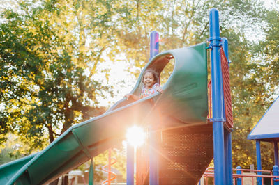 Diverse mixed race pre school girl outdoors during summer having fun at playground park 