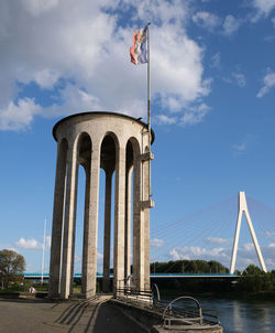 Low angle view of bridge over river against cloudy sky