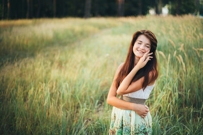 Smiling young woman standing on grassy field