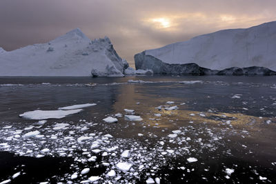 Scenic view of frozen lake by mountain against sky