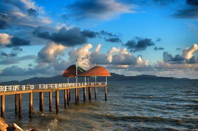 Pier on sea against cloudy sky