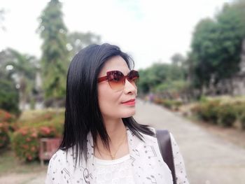 Mature woman looking away while wearing sunglasses in park