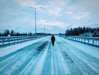 Rear view of man on snow covered road