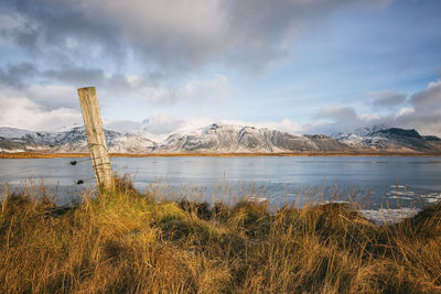 Scenic view of lake by snowcapped mountains against sky