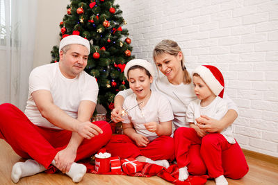 Smiling family holding gift boxes, sparkles. family celebrating xmas