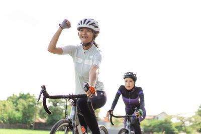 Young women riding bicycles against sky