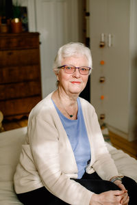Portrait of smiling retired senior woman sitting on bed in nursing home
