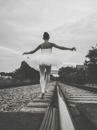 Rear view of woman with arms outstretched standing against sky