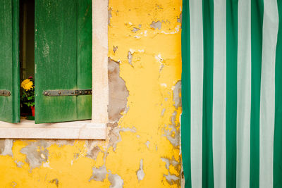 Detail of yellow colored house with window and agh curtain