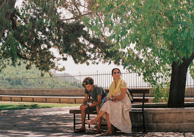 People sitting on bench against trees