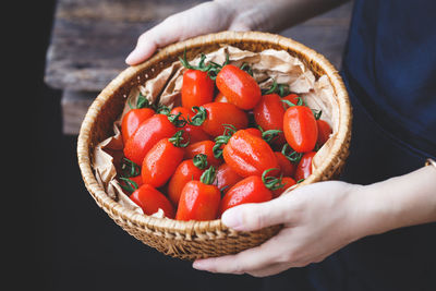 Midsection of woman holding tomatoes in basket
