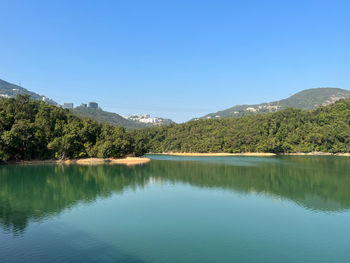 Scenic view of lake and mountains against clear blue sky