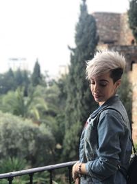 Woman standing by railing against trees