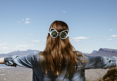 Rear view of woman wearing sunglasses against sky