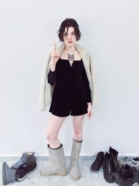 Portrait of young woman standing against wall