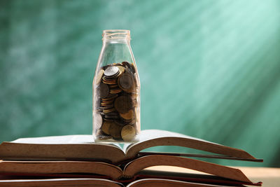 Close-up of coins in jar on open book at home