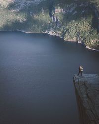 High angle view of man standing on cliff against lake