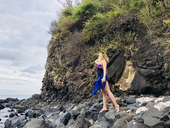 Full length of woman standing on rocks at beach