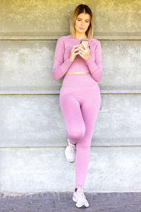 Low section of young woman standing against wall