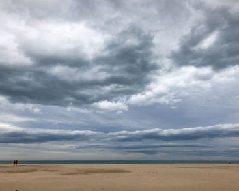 Scenic view of beach against cloudy sky