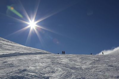 Low angle view of people skiing on snowcapped mountain against sky
