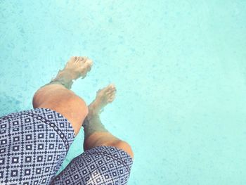 Low section of person with legs swimming in pool