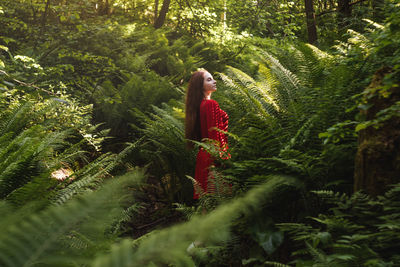 Woman standing amidst plants in forest