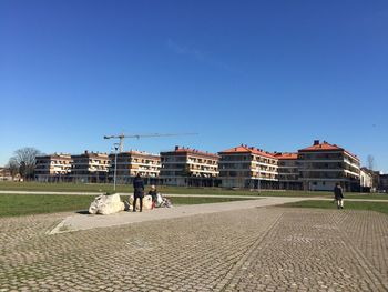 People in front of built structure against blue sky