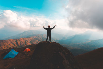 Rear view of man standing on mountain against sky