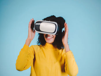 Smiling woman using vr glasses against blue background