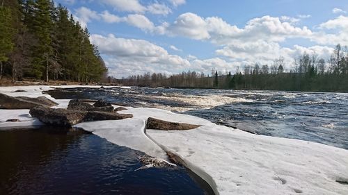 Scenic view of river against cloudy sky