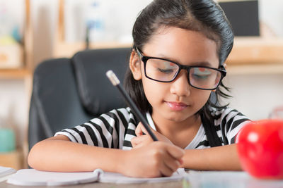 Girl writing on book at table