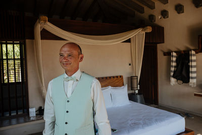 Portrait of smiling young man standing on bed