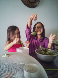 Girls cleaning vegetable while sitting at home