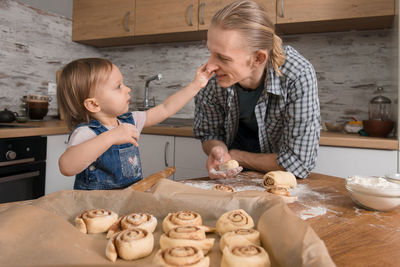 Father and child cooking on the kitchen with fun. family baking cinnabons