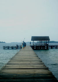 Man on pier at sea against clear sky