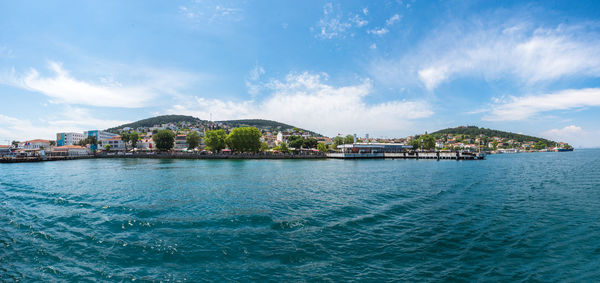 Scenic view of sea by city buildings against sky