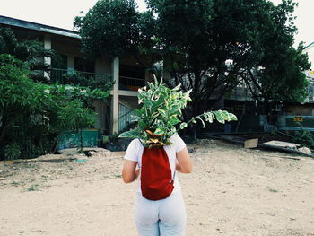 Full length of woman holding plant against trees