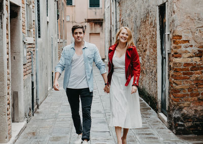 Portrait of couple holding hands while walking in alley