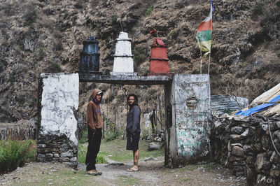 Side view of people standing under built structure against mountain