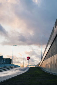 Road sign by street against sky