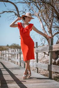 Full length portrait of young woman standing on boardwalk