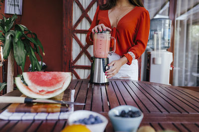 Midsection of woman holding fruit on table