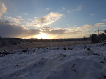 Scenic view of snow covered field against sky during sunset