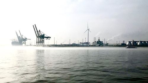 Cranes at commercial dock against sky