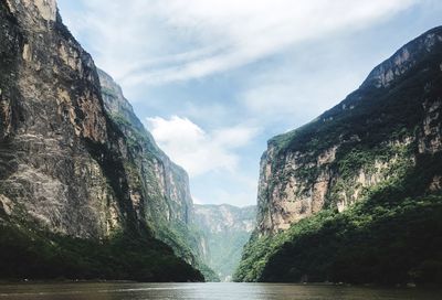 Scenic view of river amidst mountains against sky