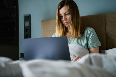 Portrait of young woman using laptop on bed at home