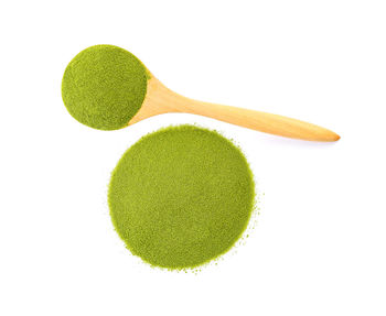 High angle view of matcha tea in wooden spoon on white background