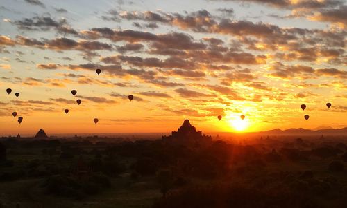 Silhouette of hot air balloons against sky during sunset